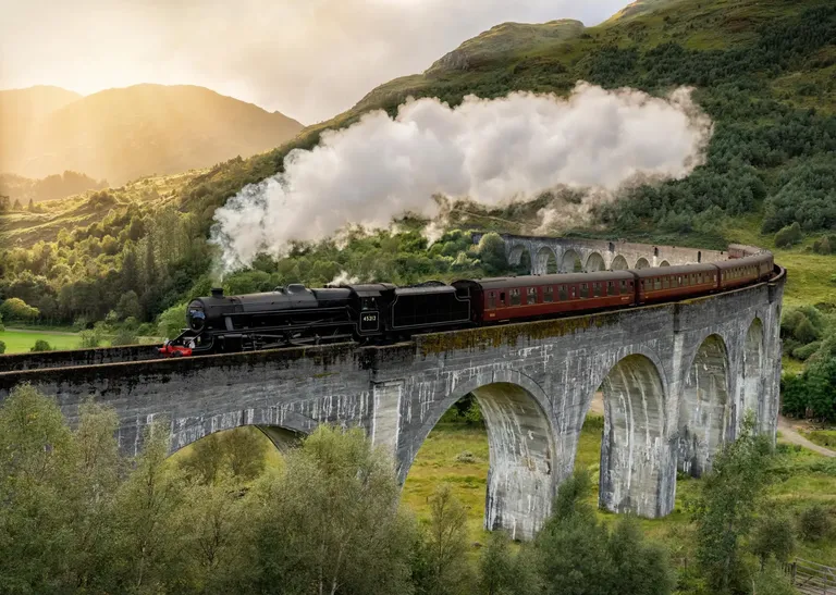 Vlak na vijaduktu u škotskom krajoliku poznatom iz filmova o Harryju Potteru